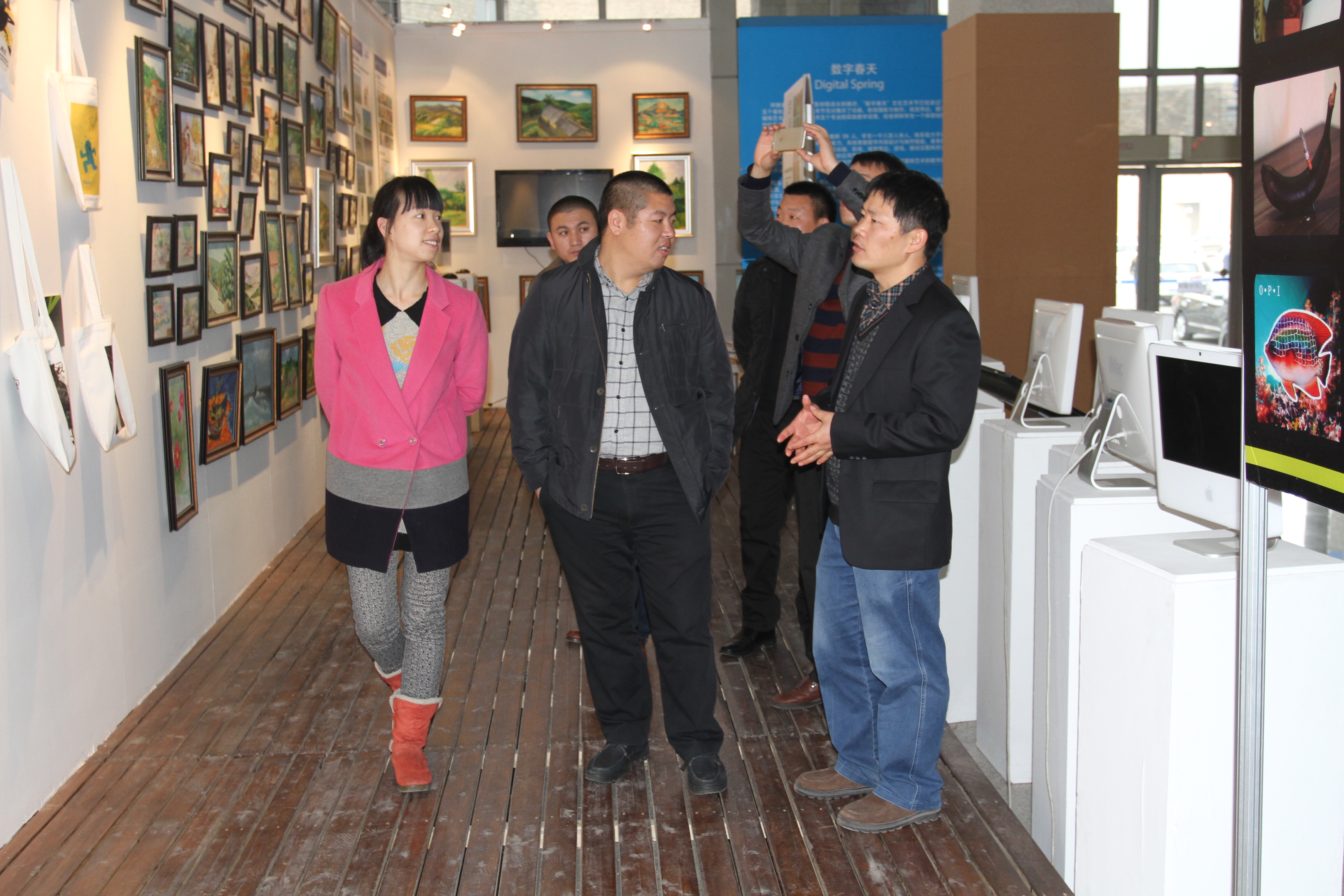 数字艺术系主任余庆军为来访嘉宾展示金色之秋作品展上的学生作品并与嘉宾亲切交流